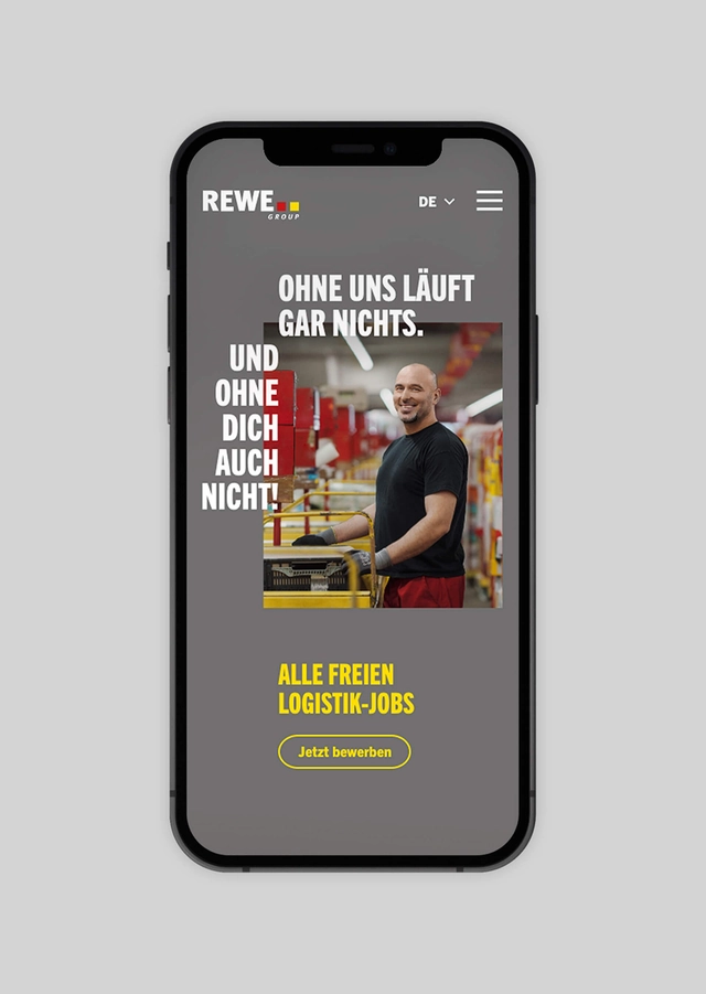 Handy mit der geöffnete Landing Page von Rewe mit dem Slogan "Ohne uns läuft gar nichts. Und ohne dich auch nicht!"